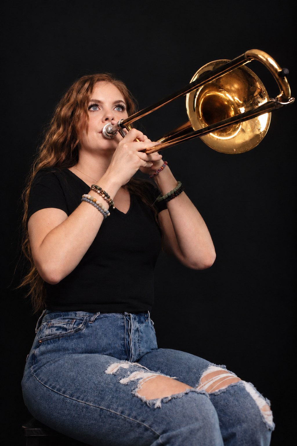 Musician playing a brass trombone against a dark studio backdrop