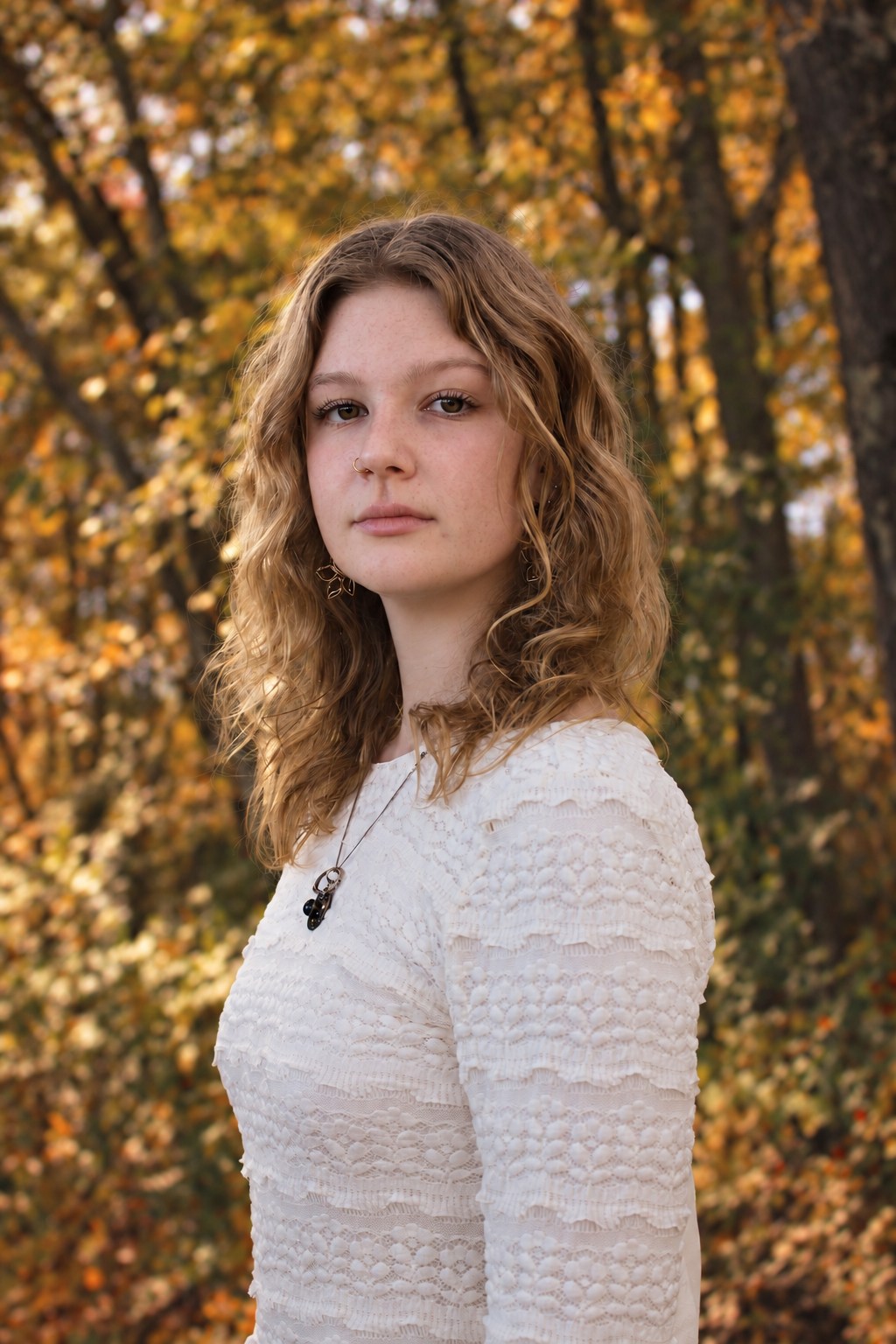 Portrait in a white lace dress surrounded by autumn leaves