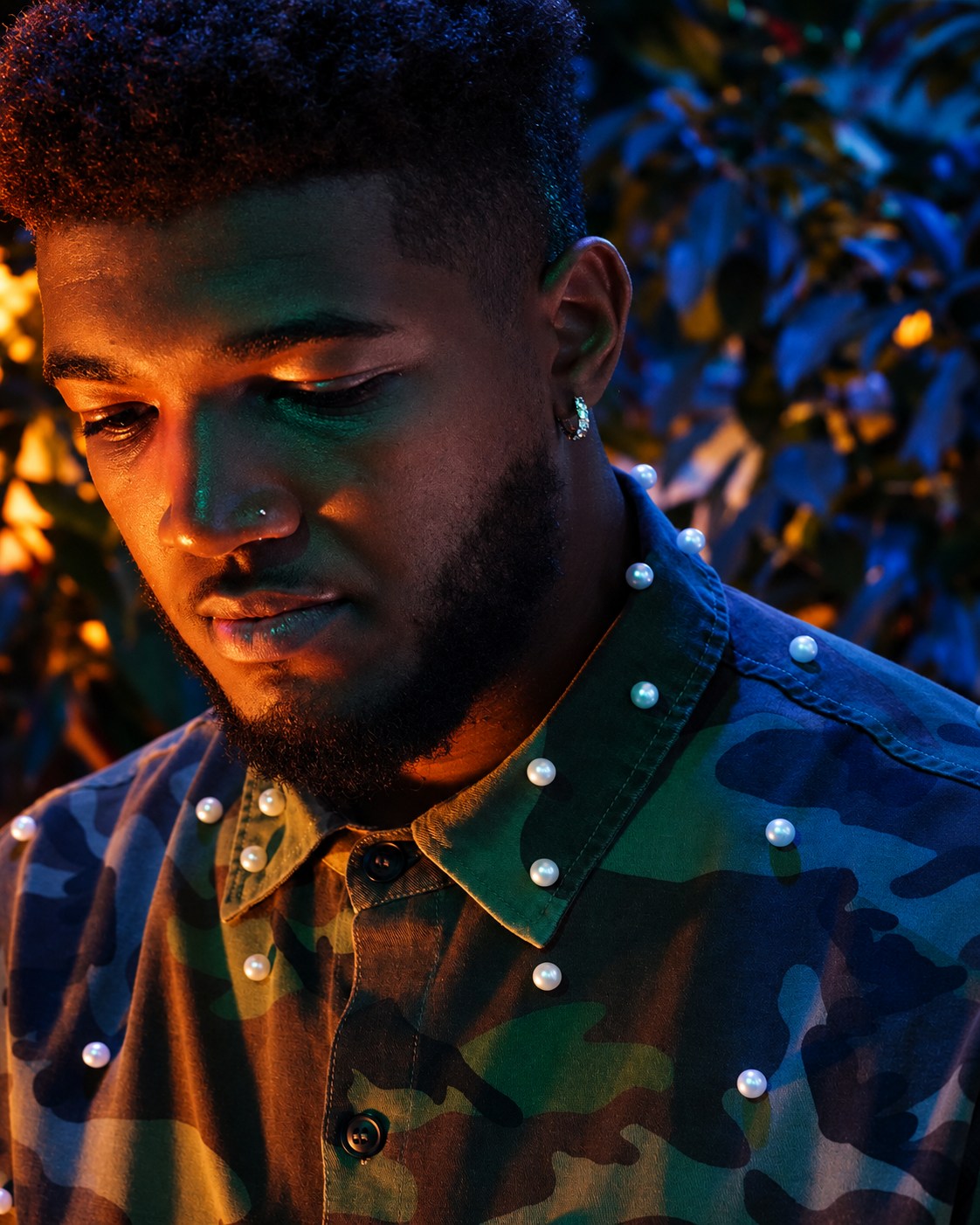 Contemplative downward-looking portrait in copper, emerald and blue light