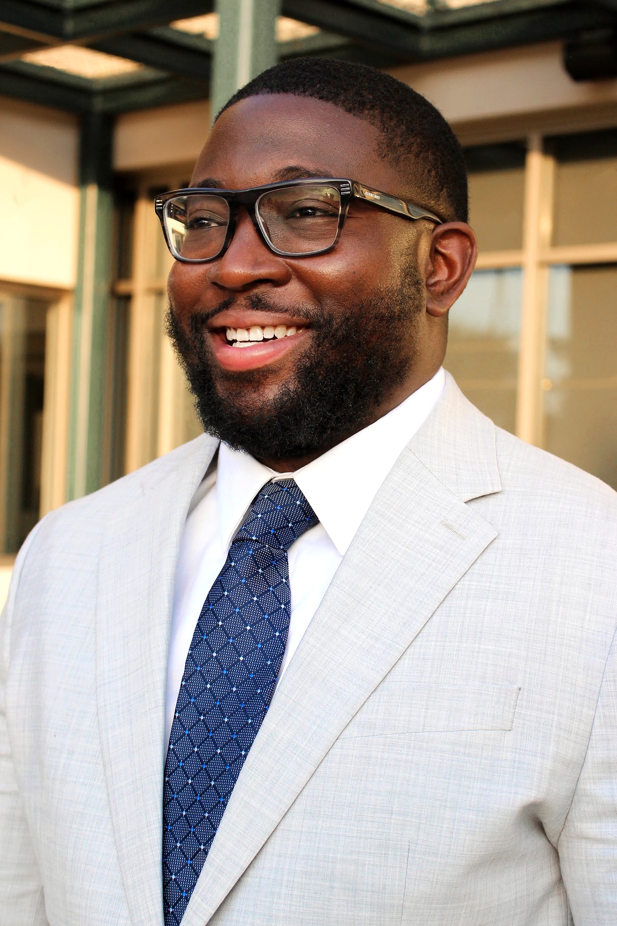 Smiling portrait in glasses, a light suit and navy tie