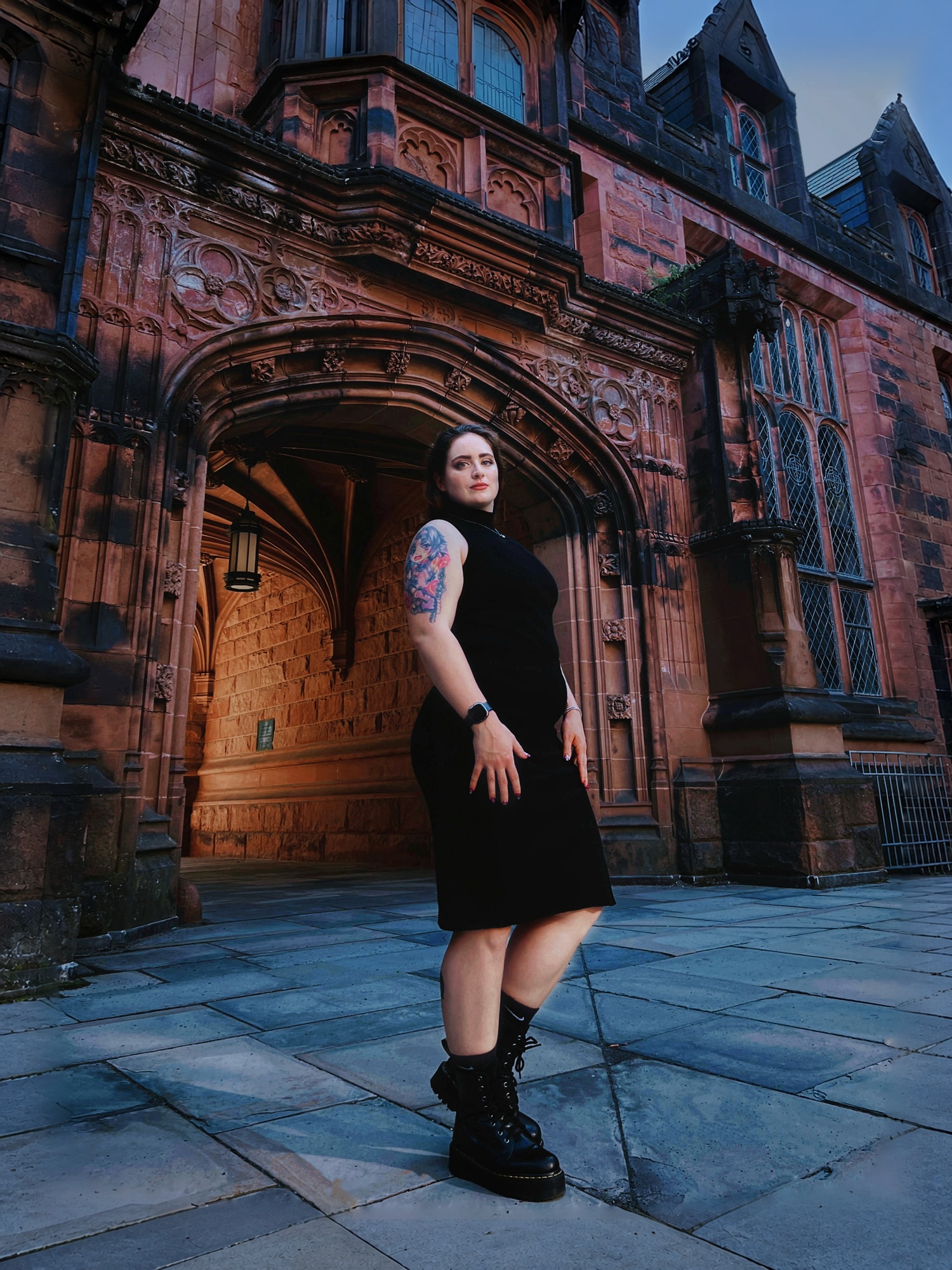 Full-length portrait in a black dress outside ornate red brick architecture