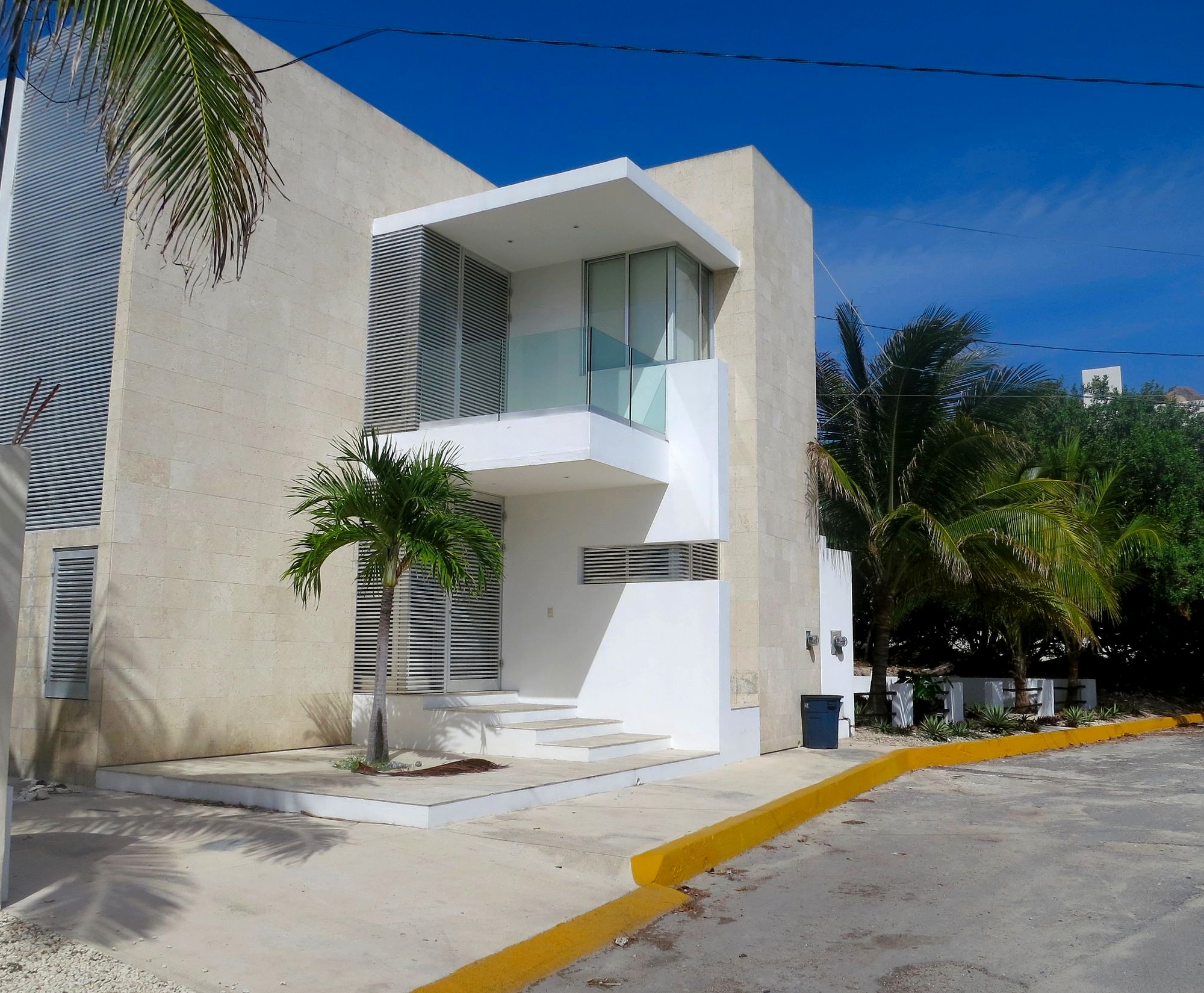Angular white architecture and palms under a blue sky