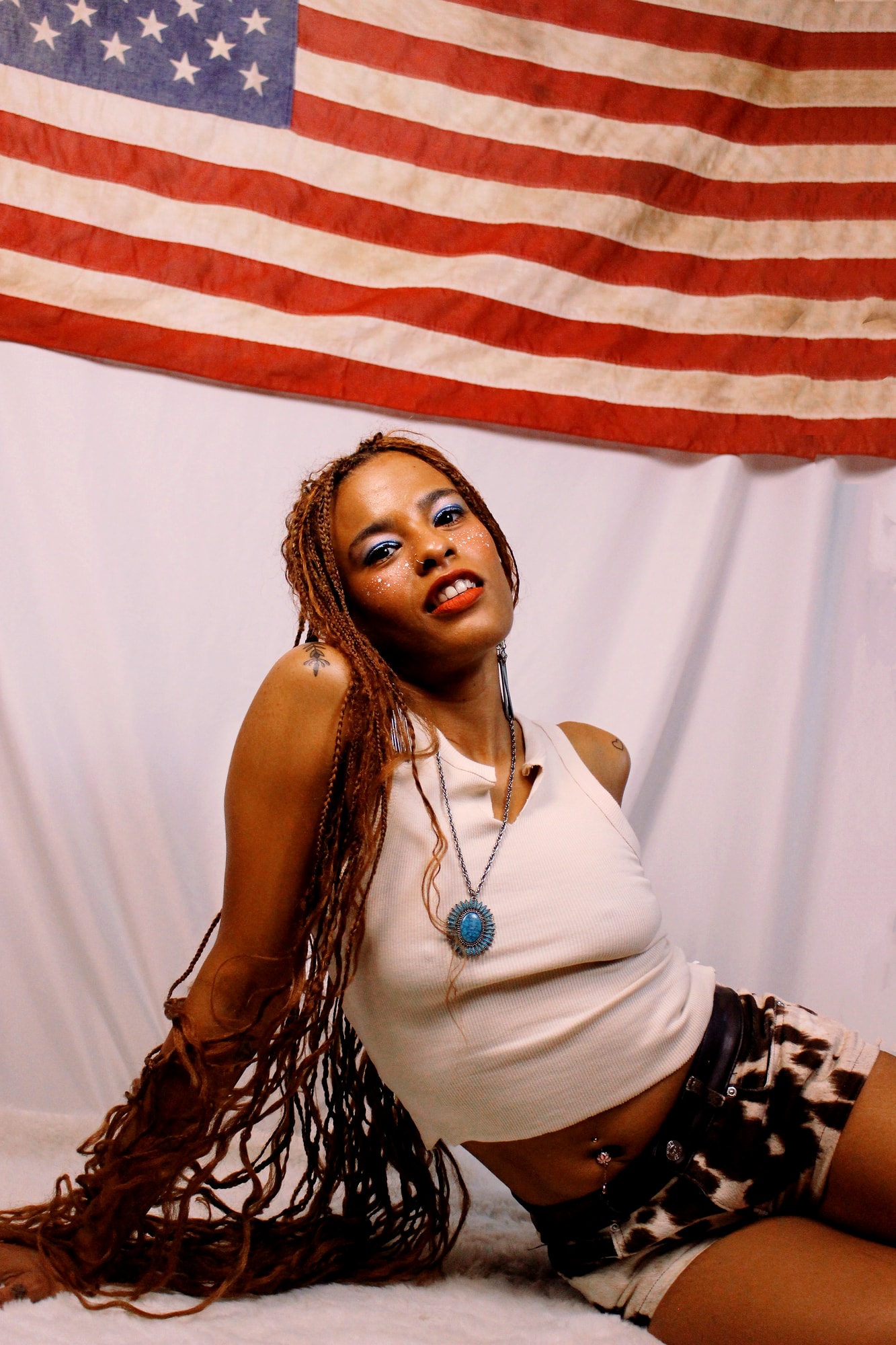 Seated studio portrait beneath an American flag