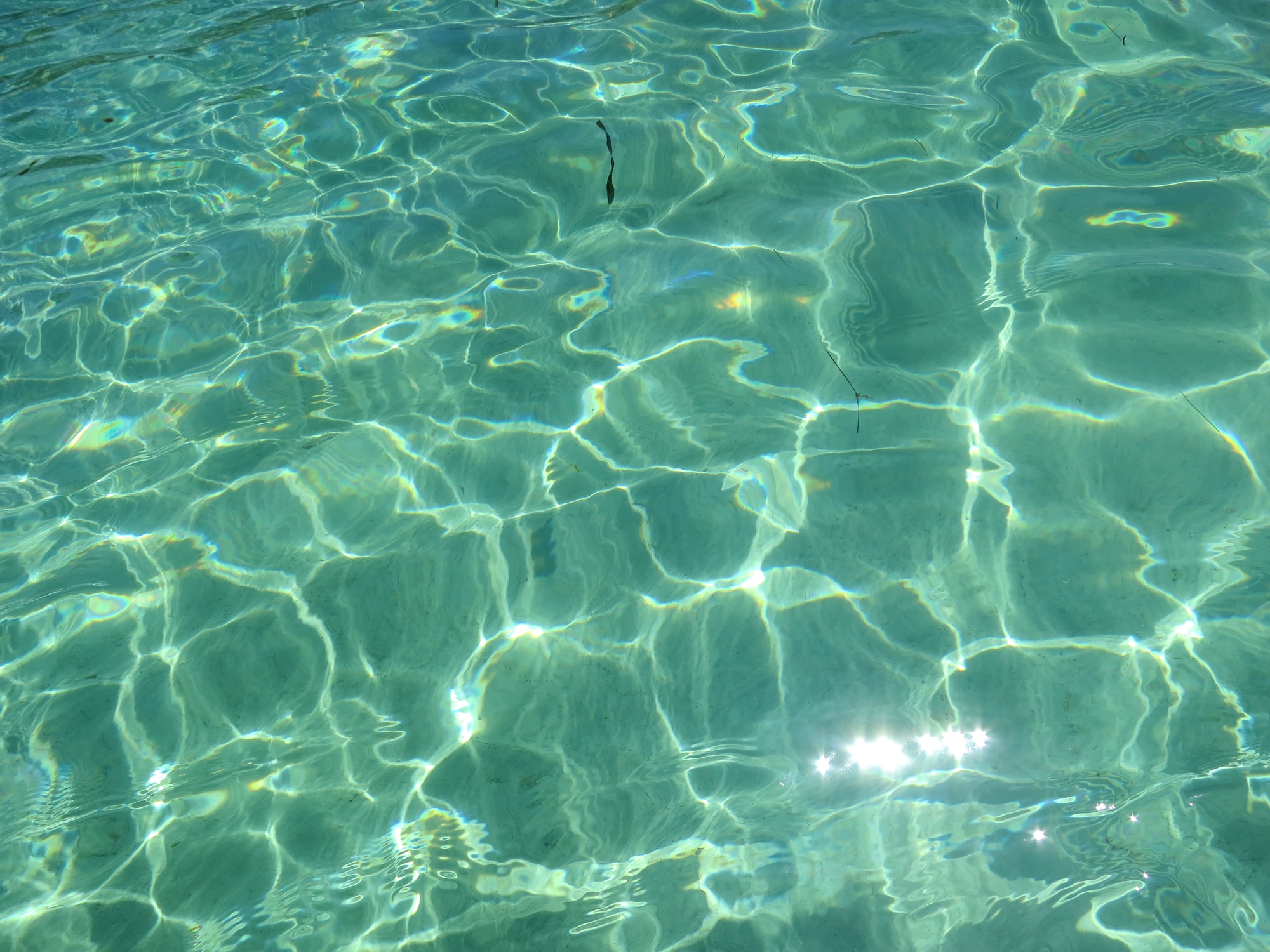 Sunlight drawing intersecting patterns across blue-green water