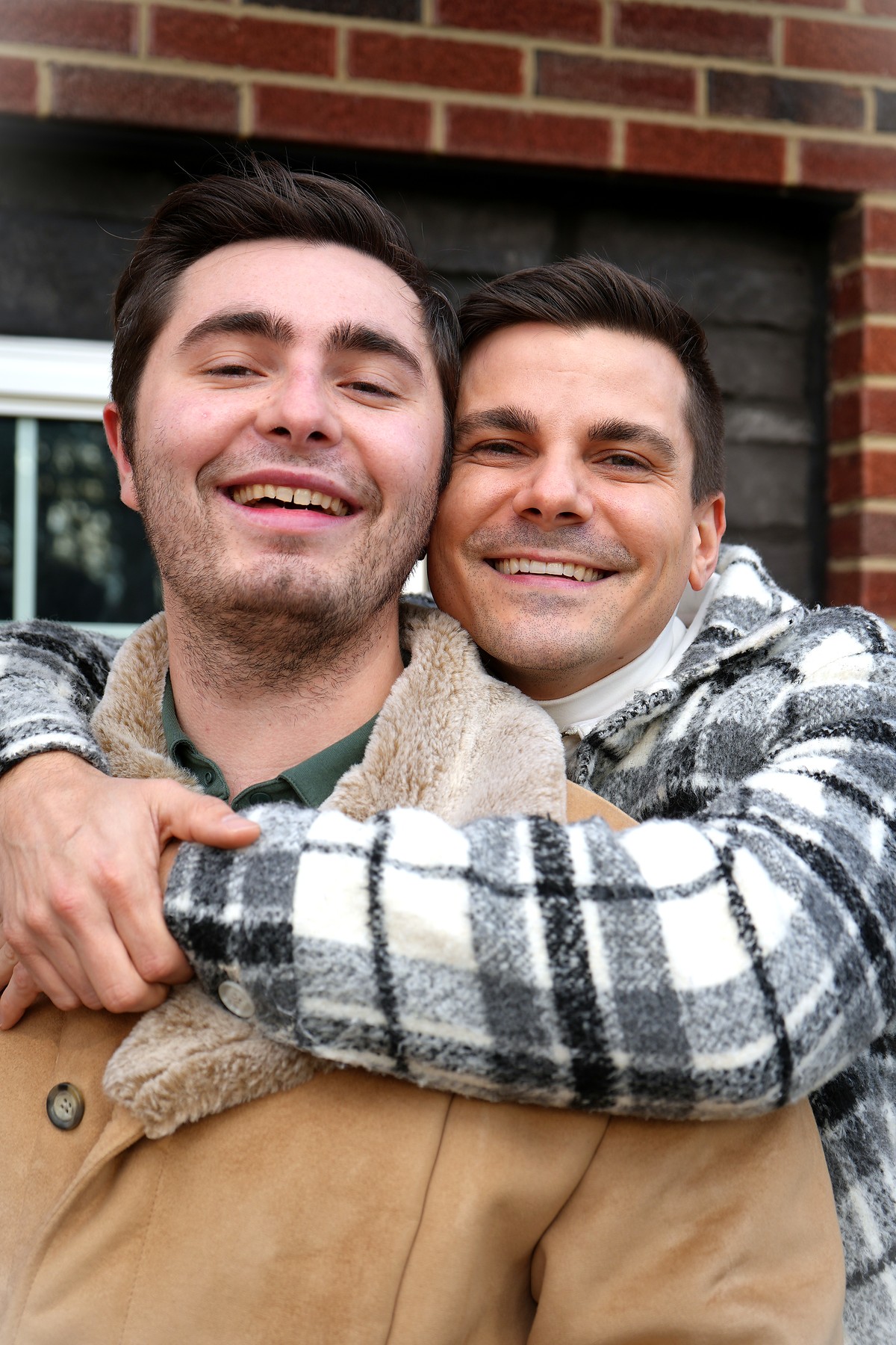Two smiling men embracing outdoors in winter coats