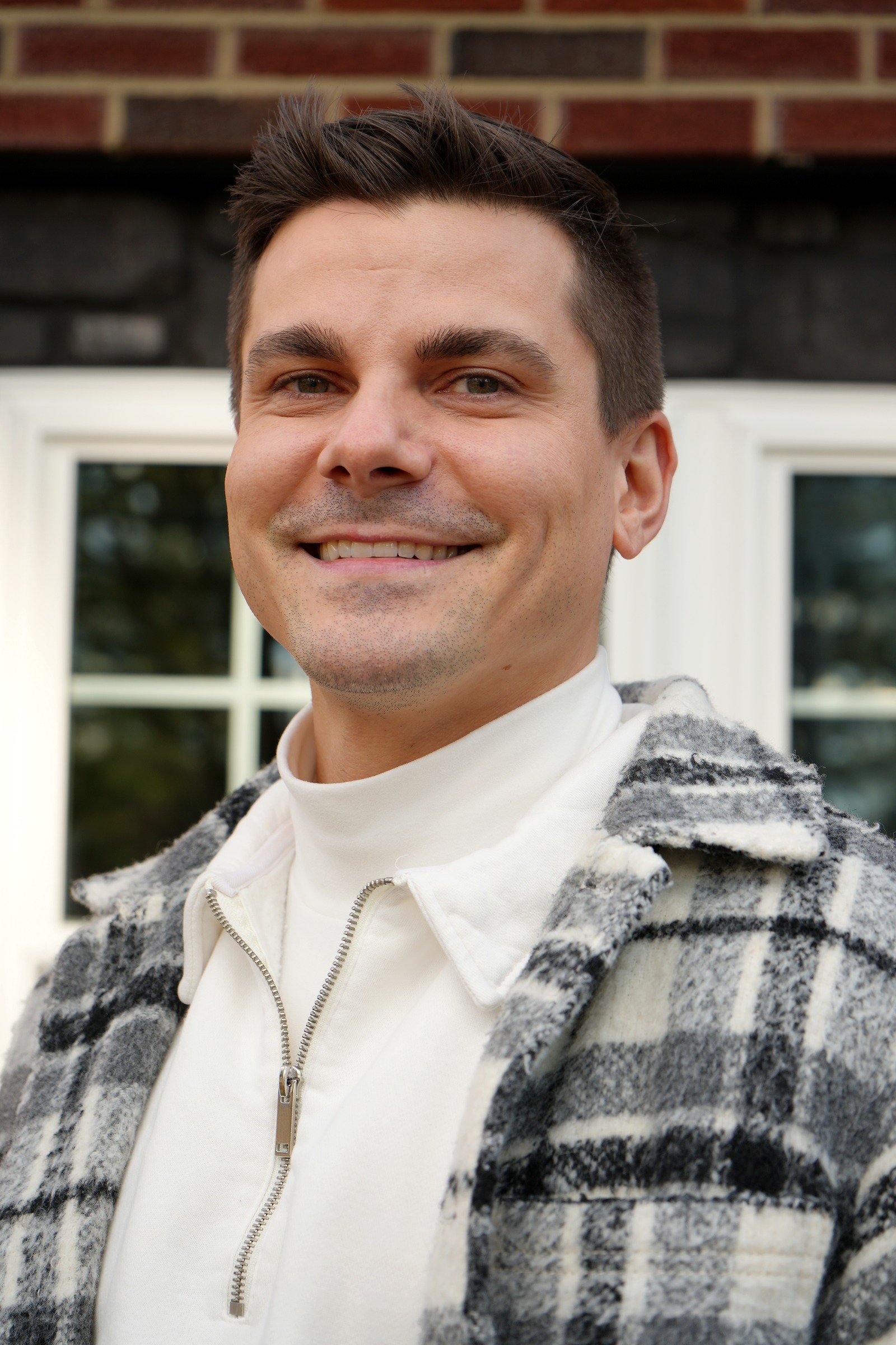 Smiling portrait in a cream turtleneck and plaid coat