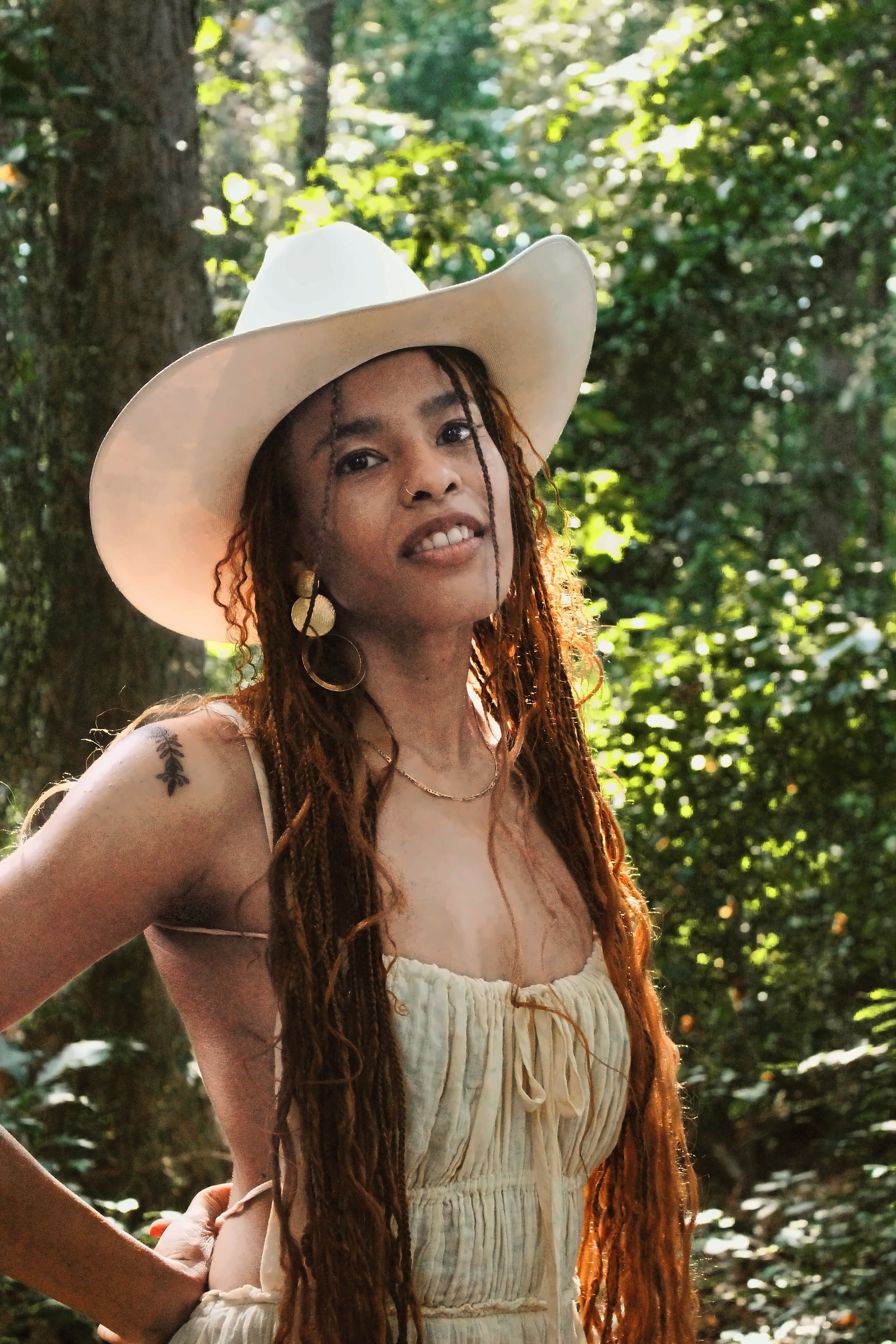 Portrait in a white cowboy hat with sunlight filtering through woodland