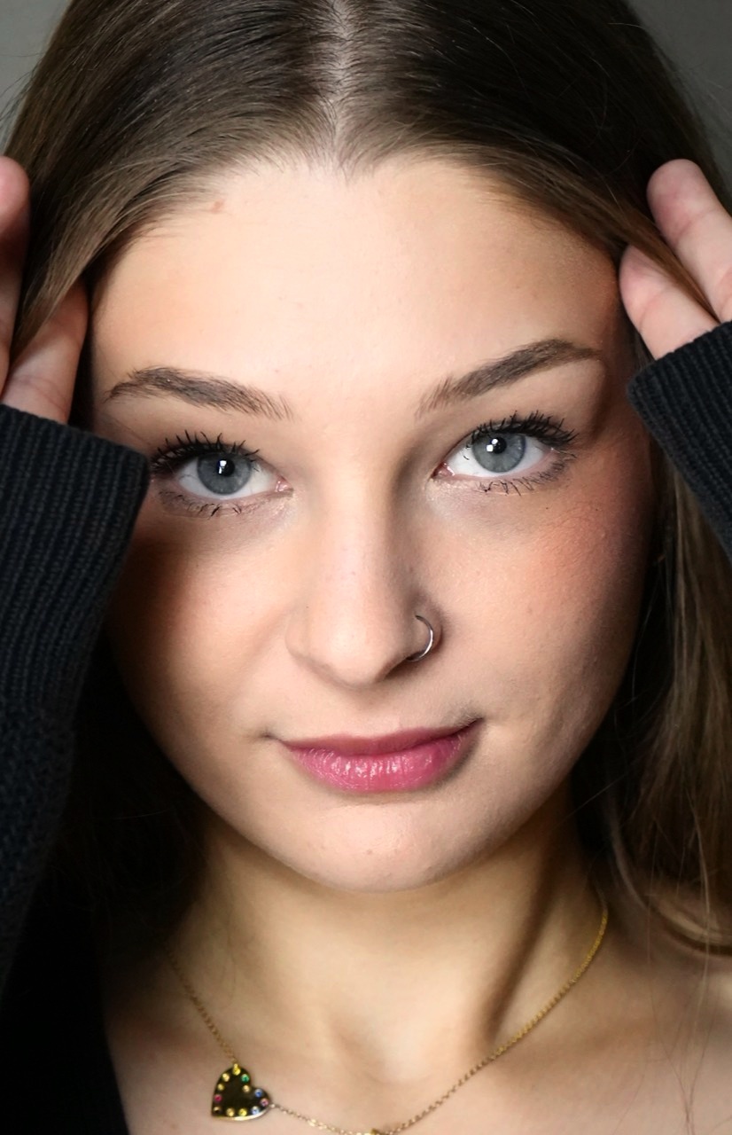Close-up portrait with blue-gray eyes and hands framing the face